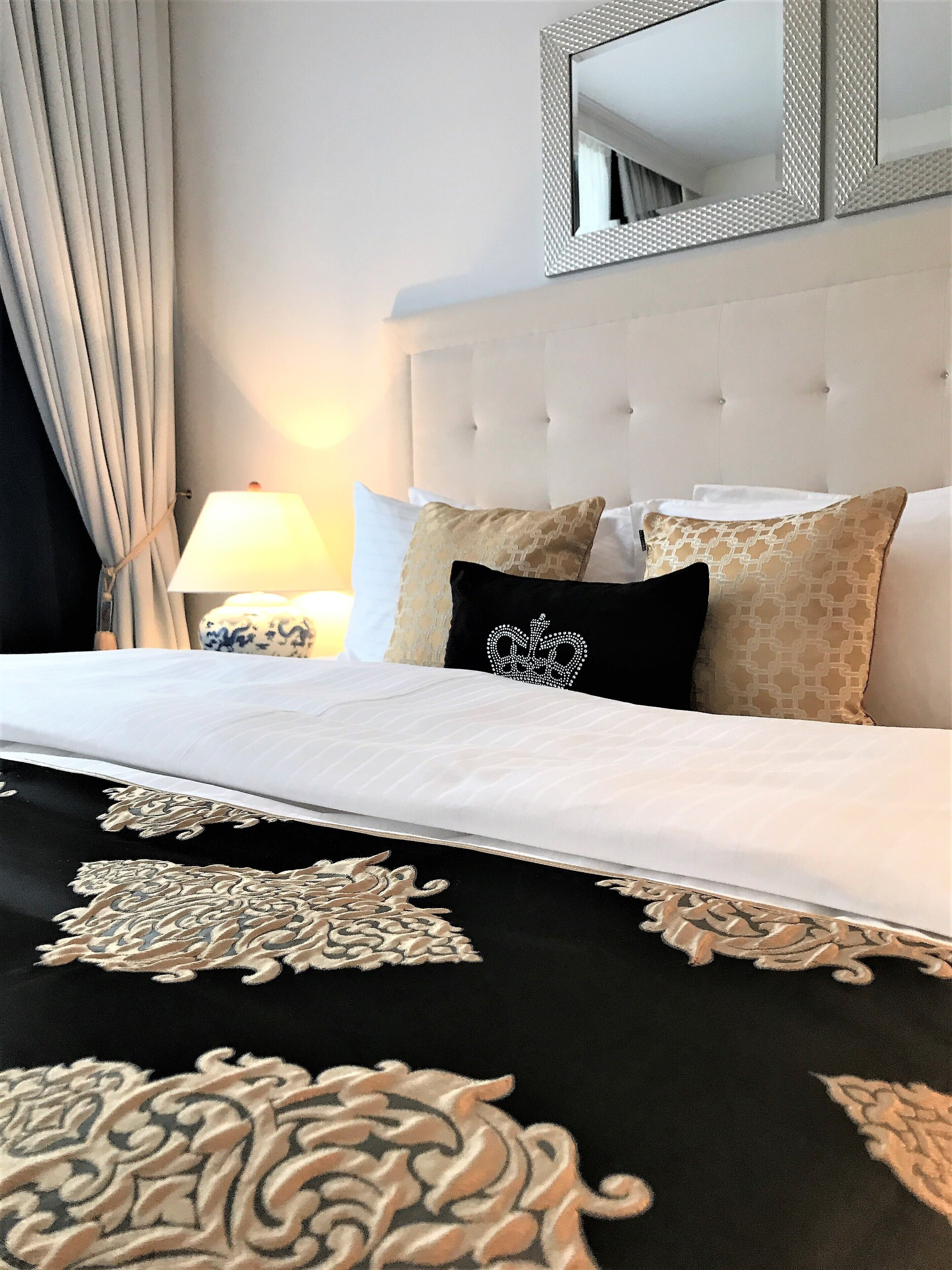 Une chambre d’hôtel avec un grand lit, une tête de lit, une table de chevet avec une lampe et un miroir au mur.