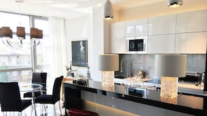 Une cuisine moderne avec des meubles blancs, un plan de travail noir et une table à manger en verre, assortie de chaises.