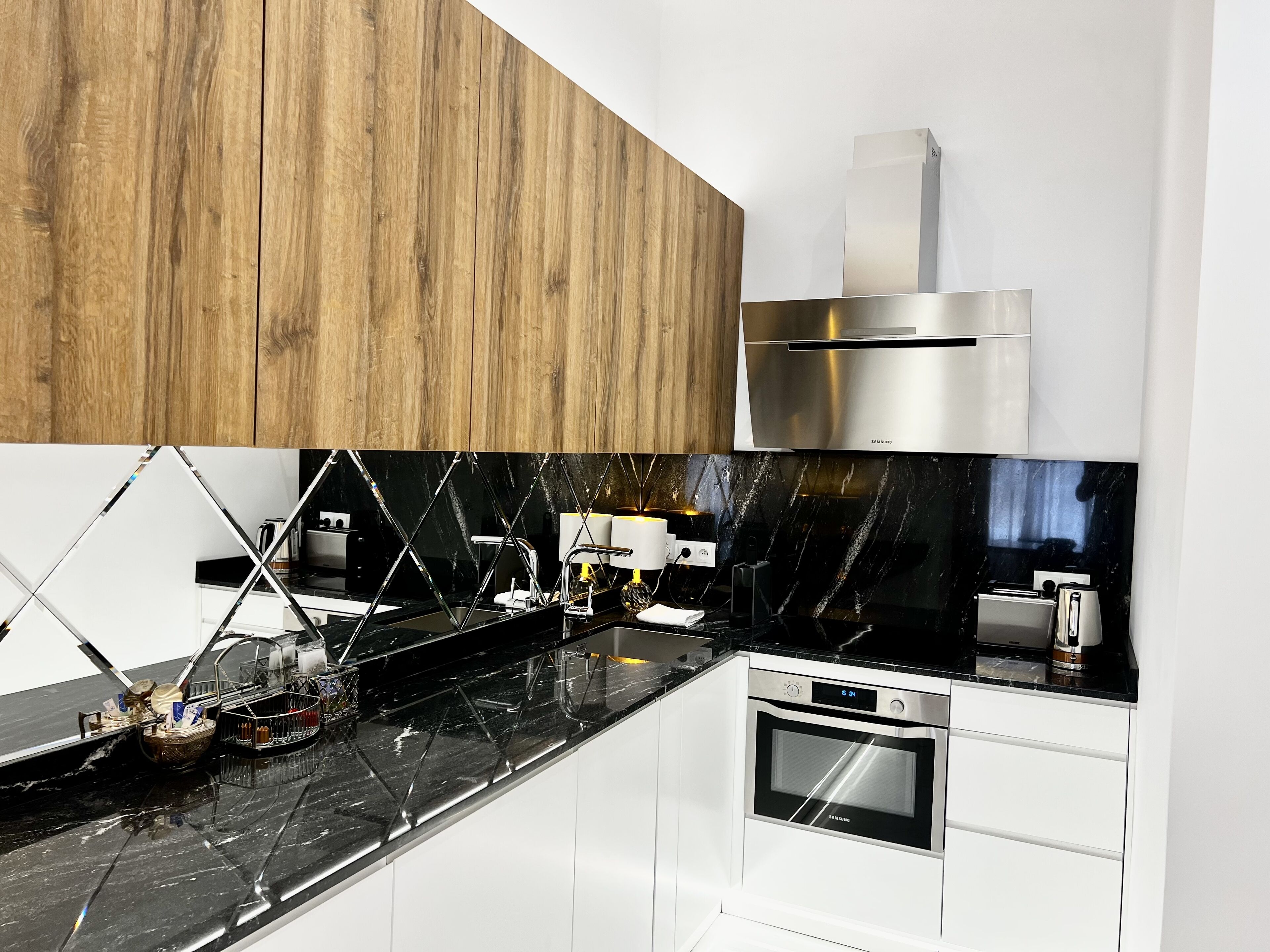 Eine moderne Küche mit schwarzem Marmorarbeitsfeld, Edelstahlgeräten und Holzschränken.