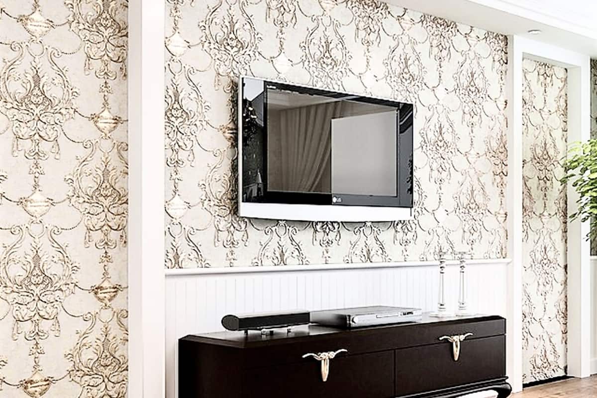 Une pièce avec un grand miroir au mur, une commode en bois foncé et un papier peint à motifs.