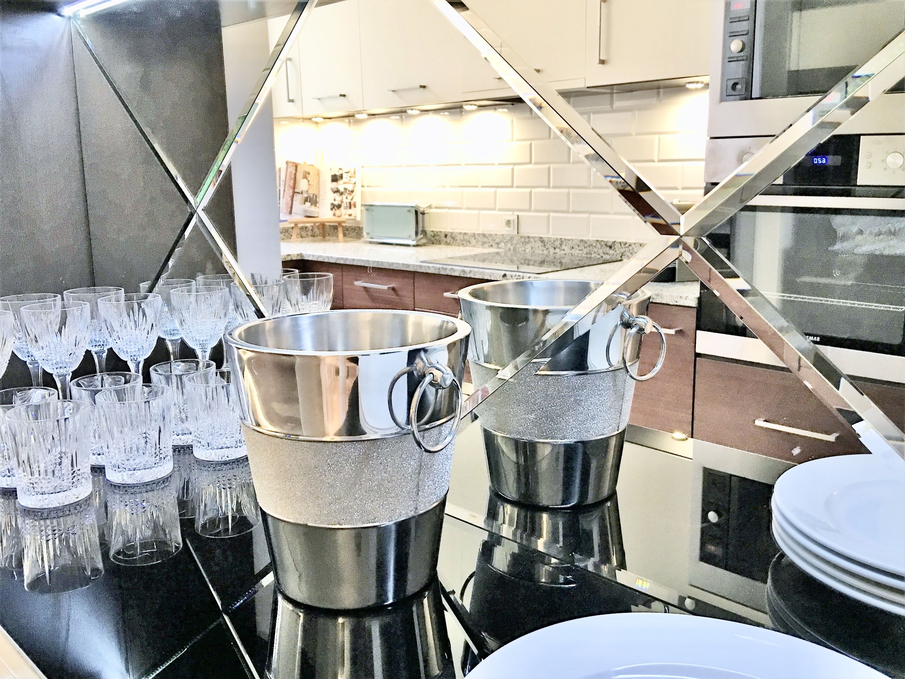 Uma cozinha com eletrodomésticos de aço inoxidável, bancada com copos e micro-ondas.