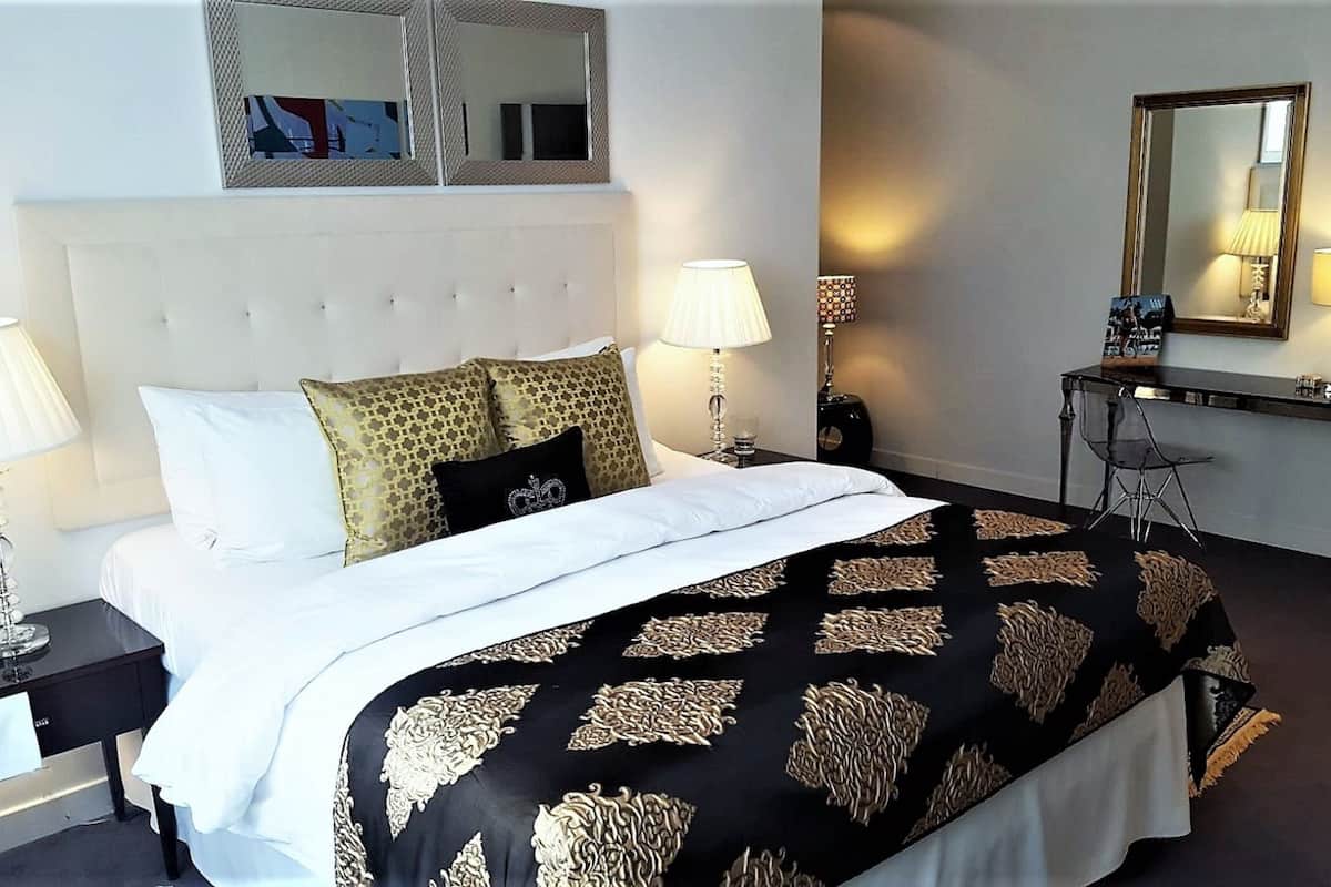 Une chambre d’hôtel avec un lit, deux tables de chevet, un bureau et une chaise.