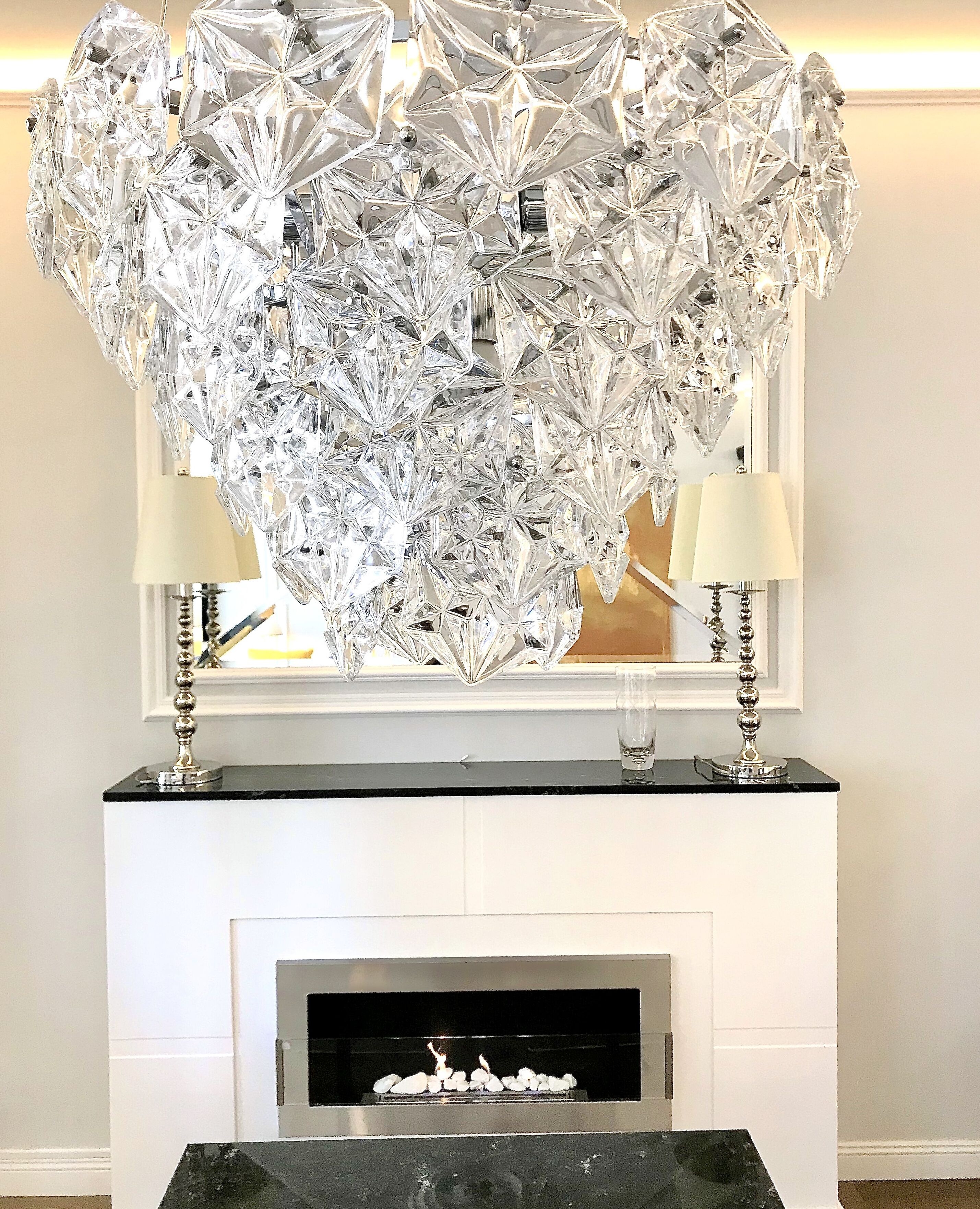 A fireplace with a modern chandelier above it.
