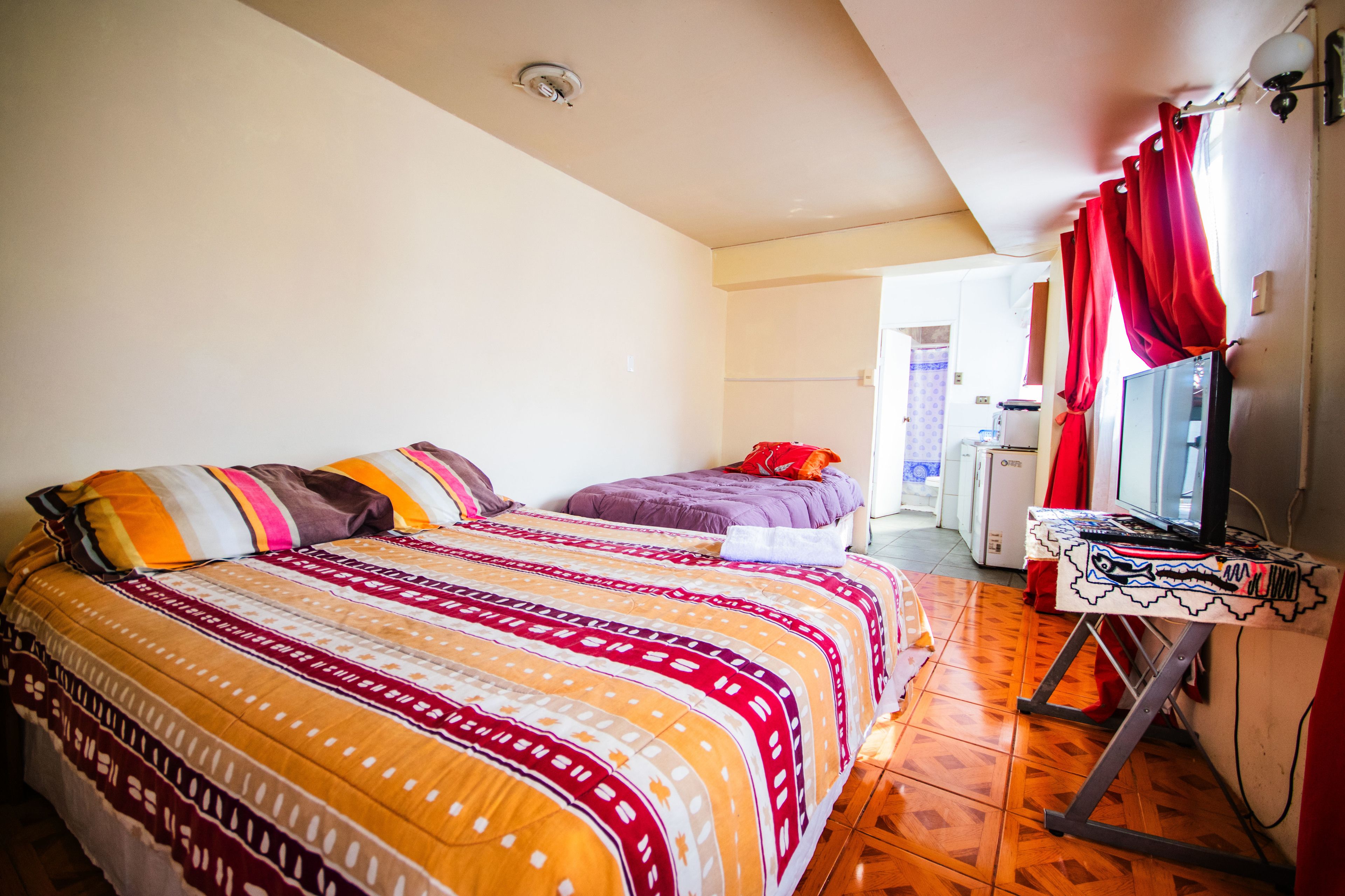 A bedroom with two beds, a television, and a desk with a computer.
