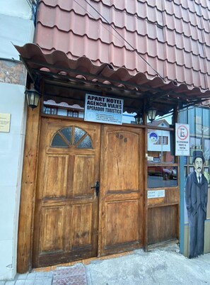 Une porte à deux battants en bois, avec une enseigne au-dessus.