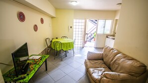A living room with a brown leather sofa, a dining table with chairs, a laptop on a table, and a staircase leading to an outdoor area. - Apart Hotel Bahia Caracoles (Antofagasta)