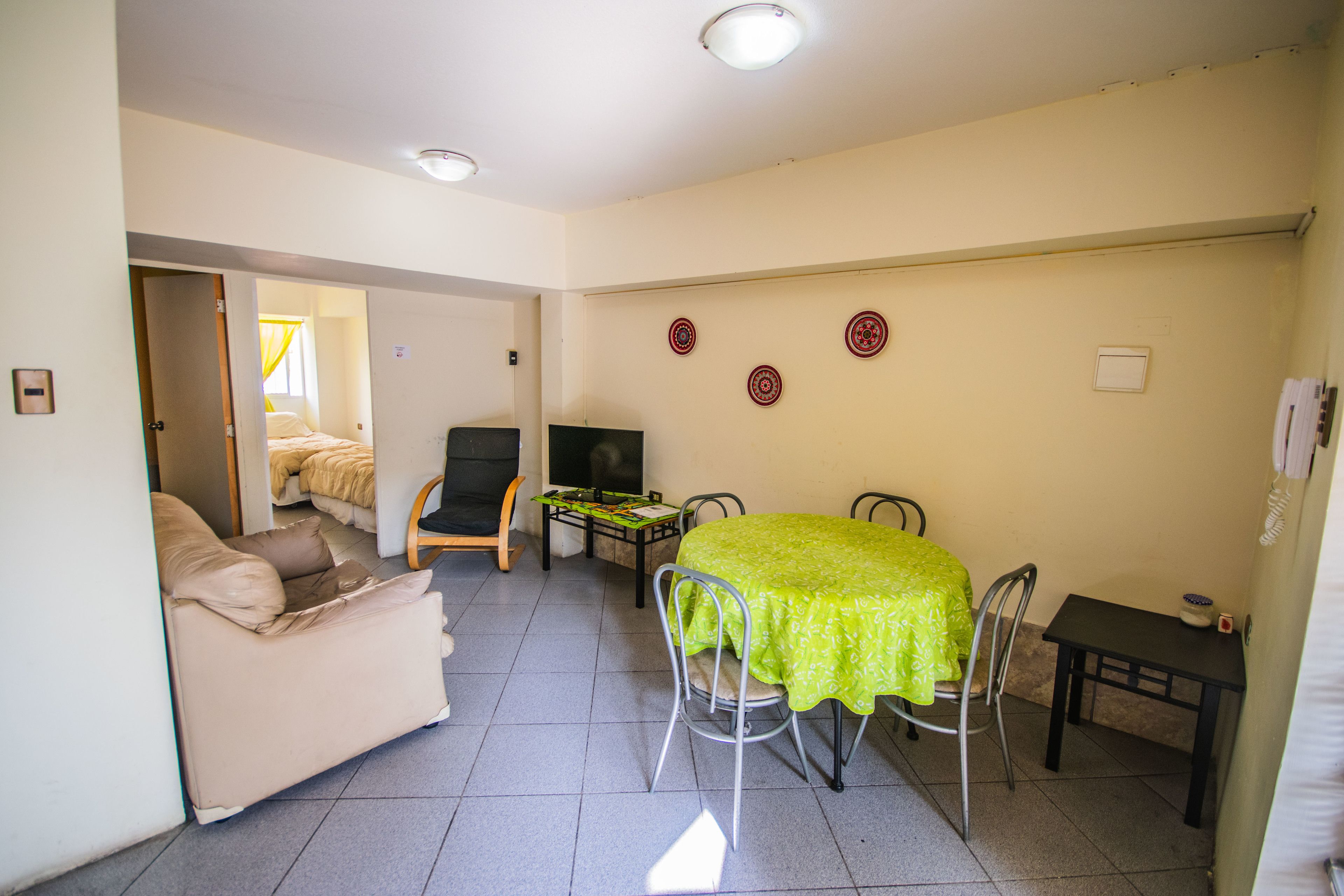 Un espacio habitable compacto con sofá, una mesa de comedor con sillas, televisor y una mesita con un cuenco.