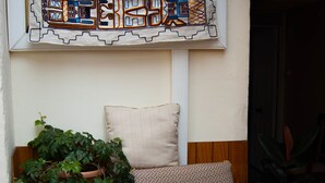 A room with a patterned armchair, a wooden chair, a potted plant, and a wall-mounted abstract artwork. - Apart Hotel Bahia Caracoles (Antofagasta)