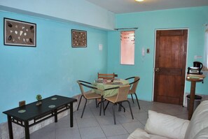 A small dining area with a table and chairs, a small table with a plant, and a door in the background. - Apart Hotel Bahia Caracoles (Antofagasta)