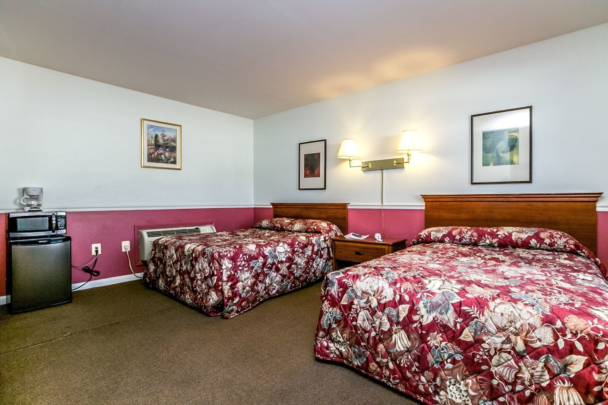 Habitación de hotel con dos camas, un escritorio, un microondas y un calefactor.