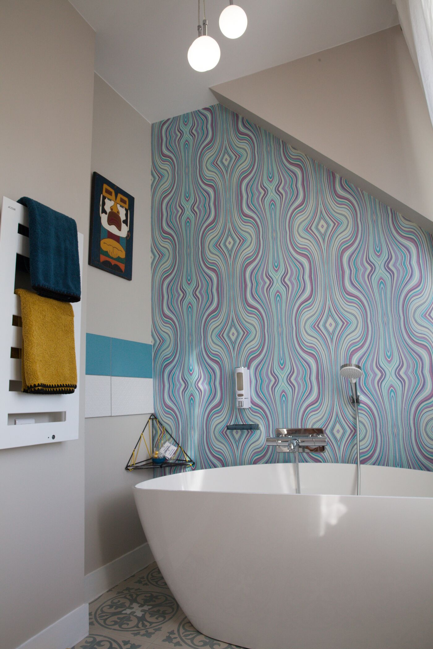 Une salle de bain moderne avec une baignoire sur pieds, un mur orné d’un motif et un porte-serviettes avec des serviettes.