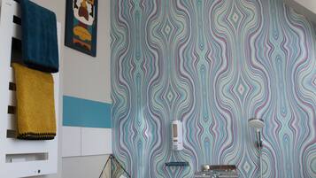 Une salle de bain moderne avec une baignoire sur pieds, un mur orné d’un motif et un porte-serviettes avec des serviettes.
