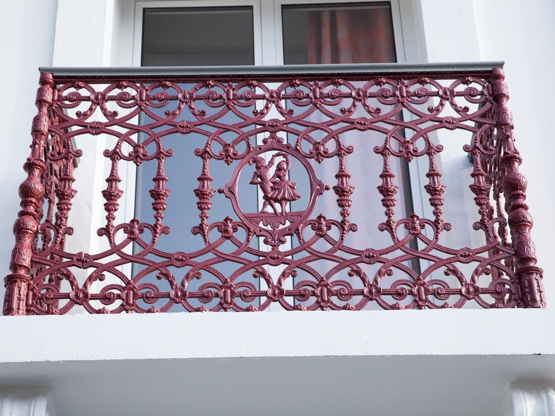 Un balcon orné de balustrades en fer forgé et une fenêtre au-dessus.