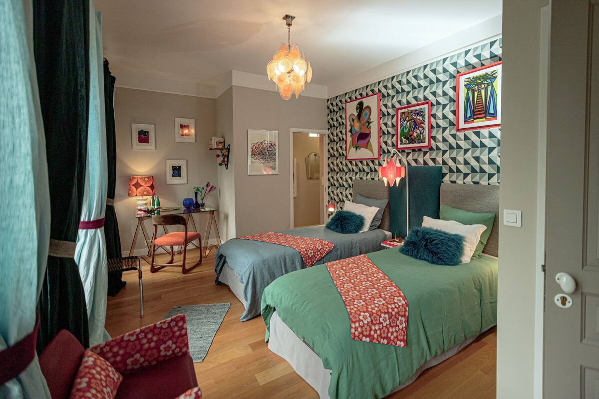 A bedroom with two beds, a desk, and a chair.