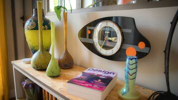 A shelf with decorative vases, a book titled 'Design', and a wall clock.