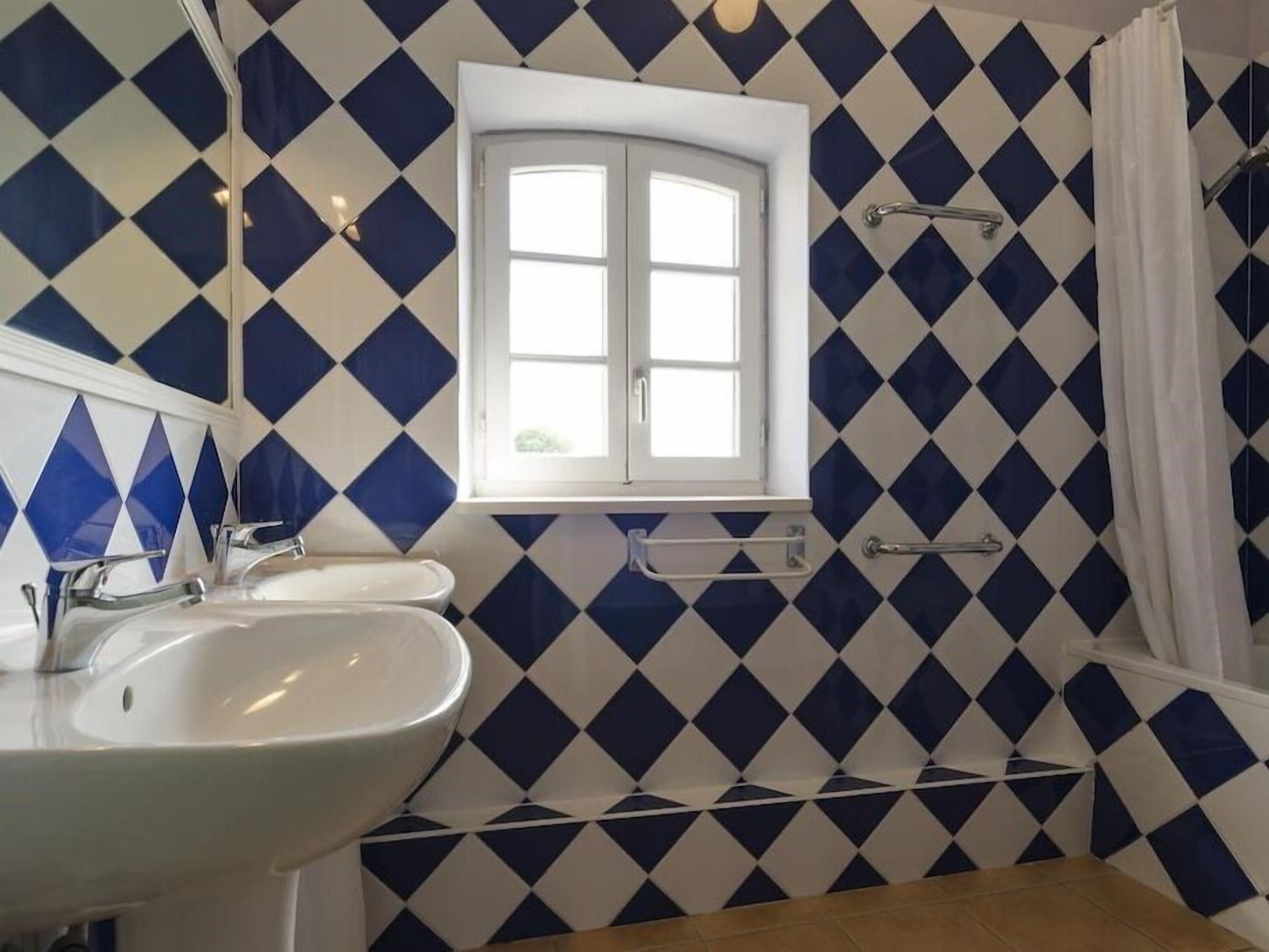 Un bagno con un lavandino bianco, una finestra e uno spazio doccia.