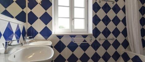 Un bagno con un lavandino bianco, una finestra e uno spazio doccia.