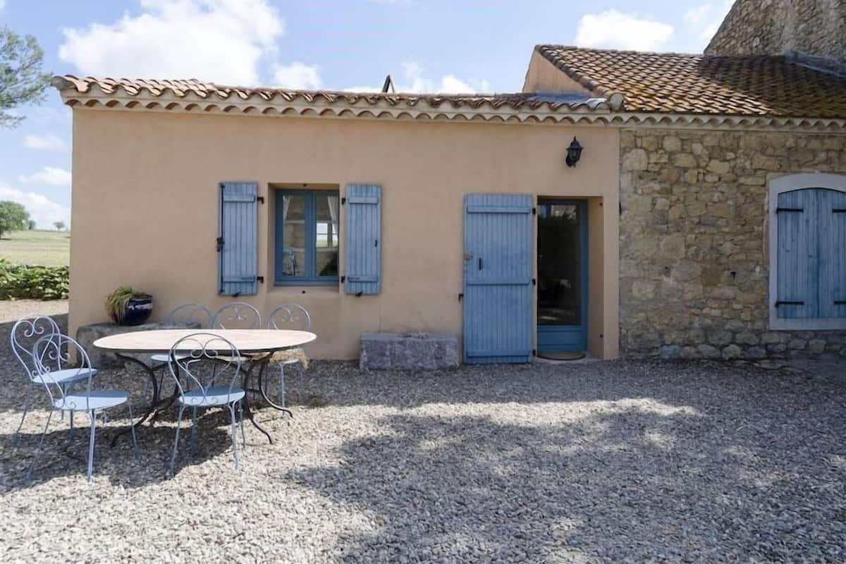 Un bâtiment doté d’une façade en pierre et d’un toit recouvert de tuiles. On y trouve un petit patio avec une table et des chaises.