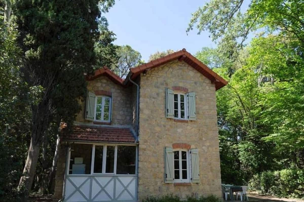 Un bâtiment en pierre doté d’un toit à pignon, de deux fenêtres avec volets et d’un petit porche.