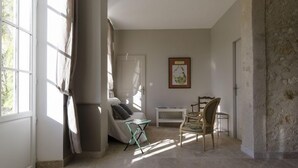 A spacious room with a large window, a bed, a desk, and a chair. - Gîtes Pech-céleyran (Salles-d'Aude)