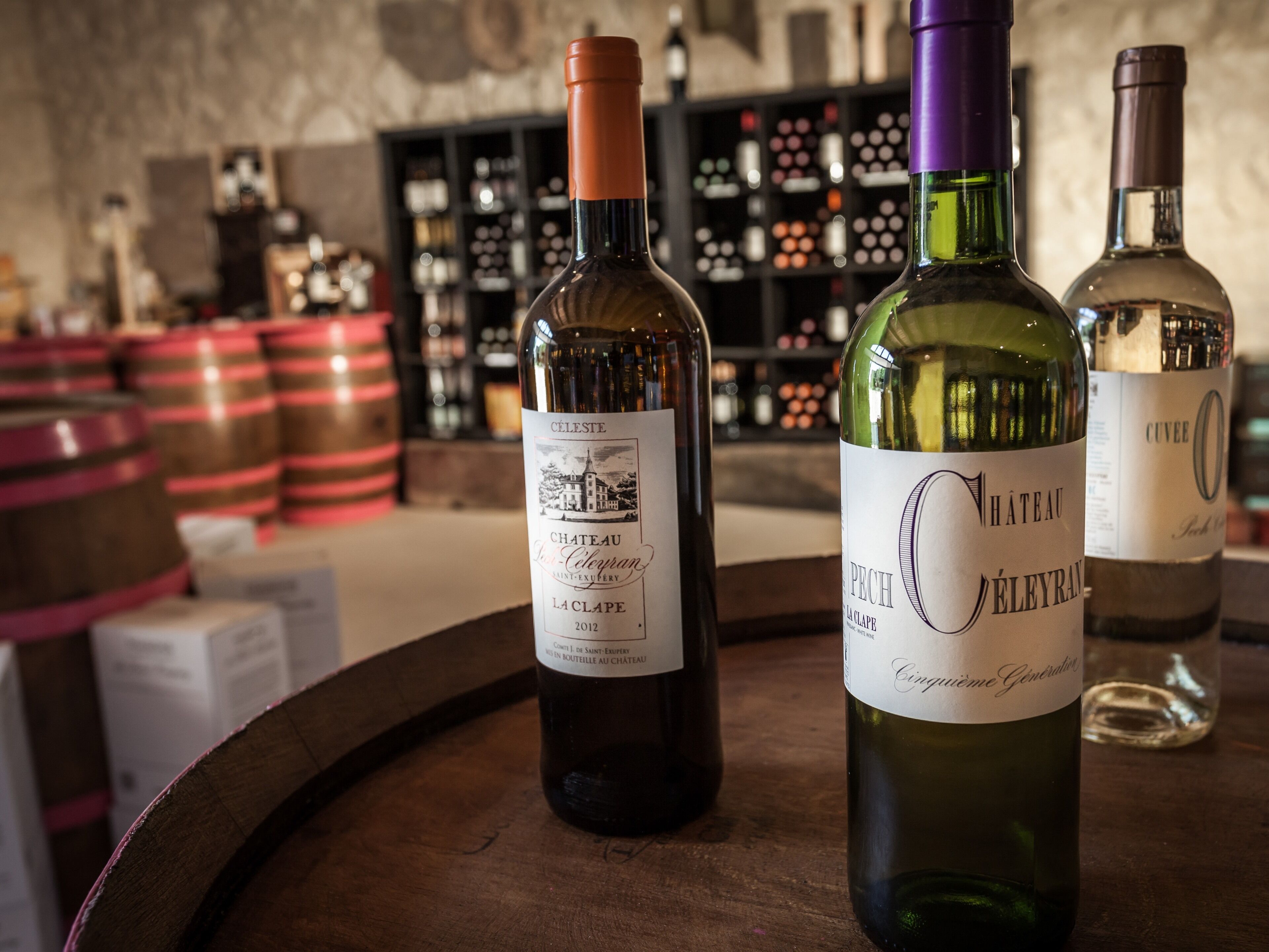 Tres botellas de vino sobre un barril de madera.