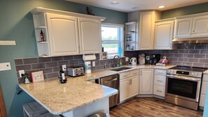A modern kitchen with white cabinets, a stainless steel oven, and a granite countertop. - Deals on Summer Sunsets! Aug 24-28, Aug 31-Sept 4. Spacious Oceanfront w/wifi (Grayland)