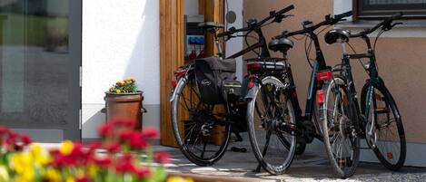 Deux vélos sont garés devant un bâtiment dont la porte est en bois et qui possède une fenêtre avec un rideau.