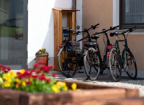 Two bicycles parked outside a building with a wooden door and a window with a curtain. - Hotel Gasthof Rosenwirt (Au in der Hallertau)