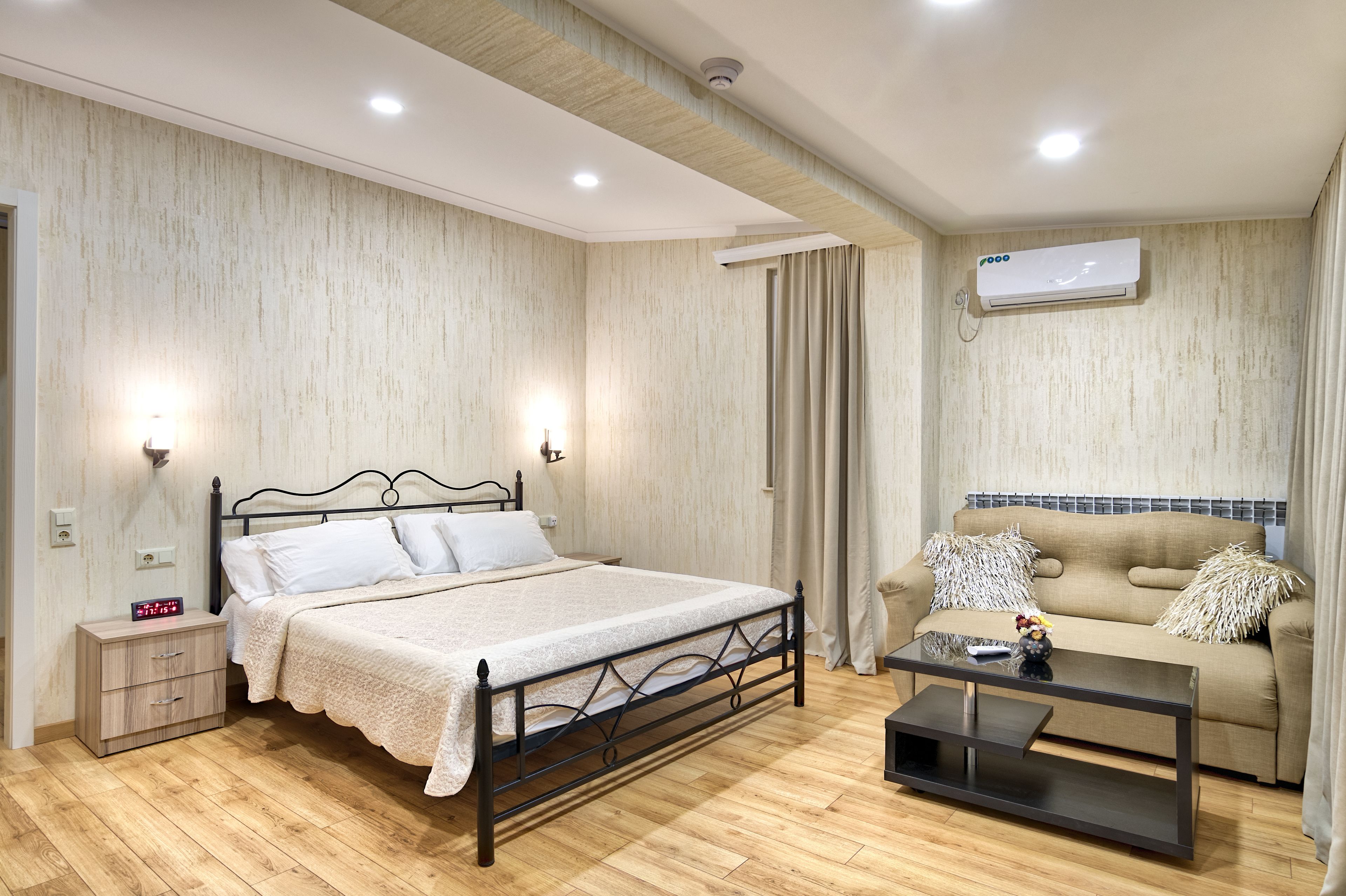A bedroom with a bed, bedside table, nightstand, and a sofa with a coffee table.