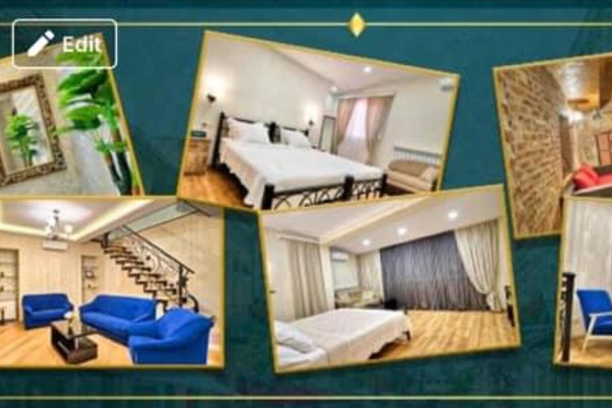 A hotel interior with a bed, blue sofas, a staircase, and a dining area.