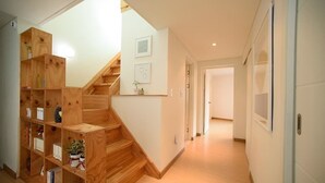 A modern interior with a wooden staircase, built-in shelving, and a hallway leading to another room. - Stay Young (Seoul)