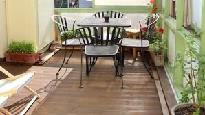 A conservatory with a wooden floor, a table with chairs, and potted plants. - Stay Young (Seoul)