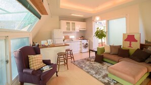 A compact living space with a kitchenette, a dining area, and a seating area with a sofa and armchairs. - Stay Young (Seoul)