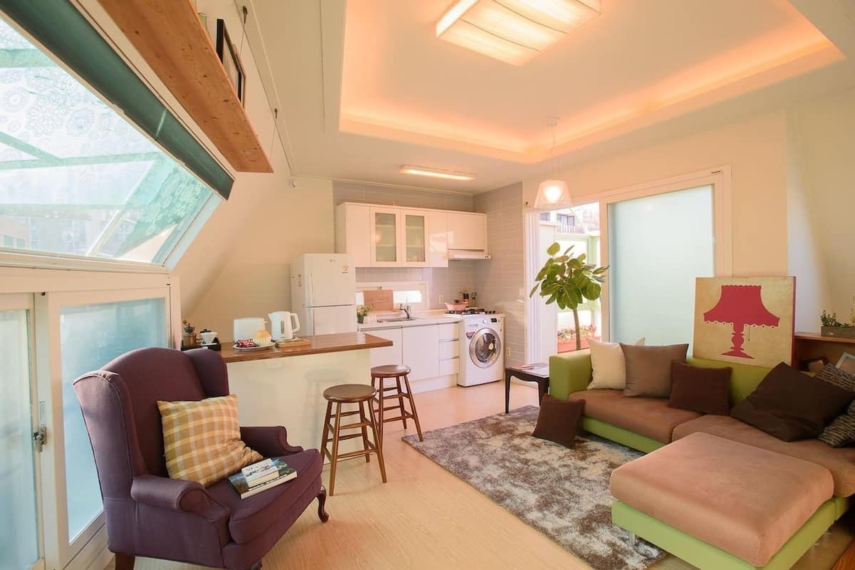 A compact living space with a kitchenette, a dining area, and a seating area with a sofa and armchairs.
