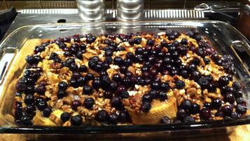 Un plat en verre contenant un dessert aux fruits, peut-être une charlotte ou une croustade, posé sur un comptoir en bois.