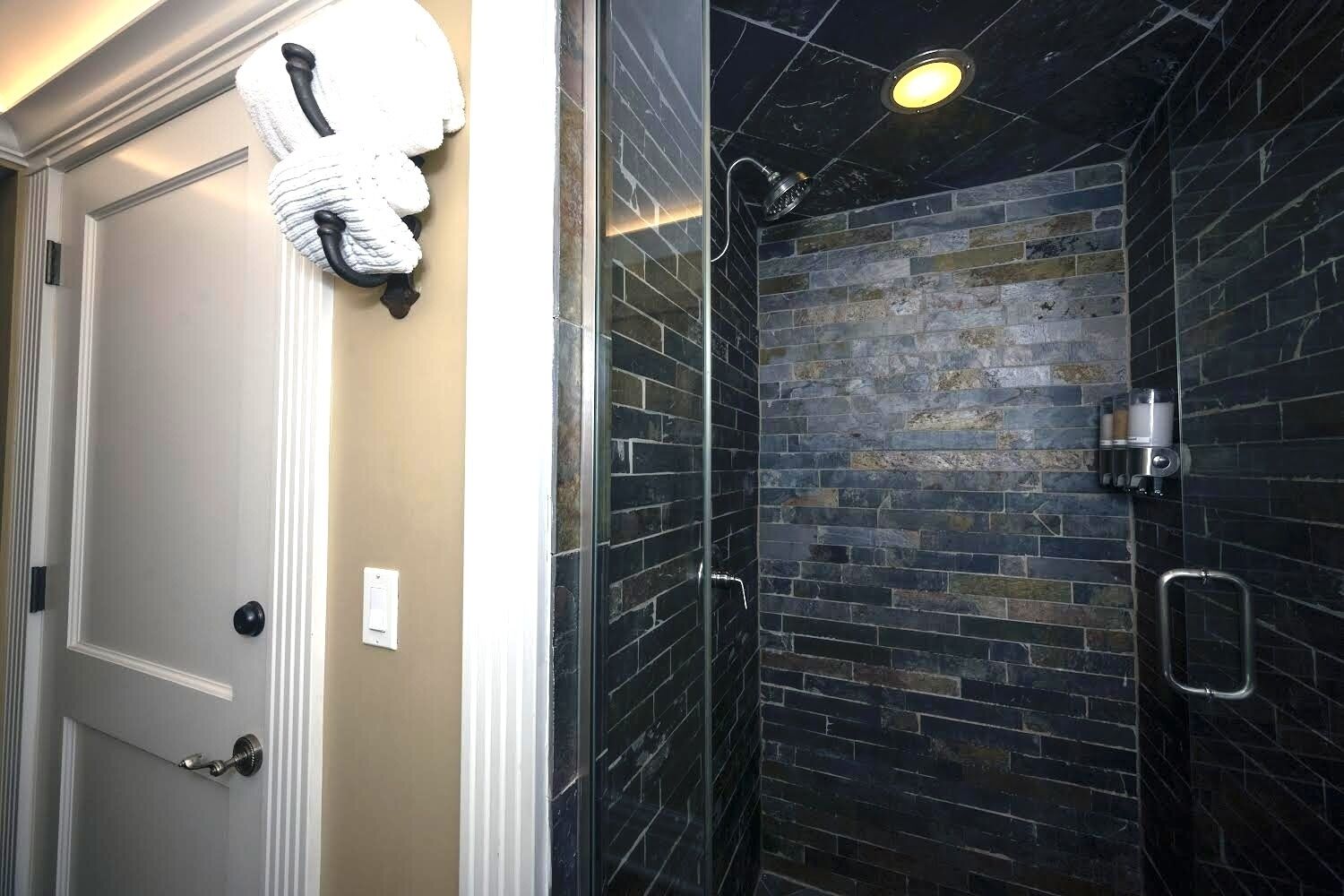 Un baño con ducha, toallero y puerta con picaporte.