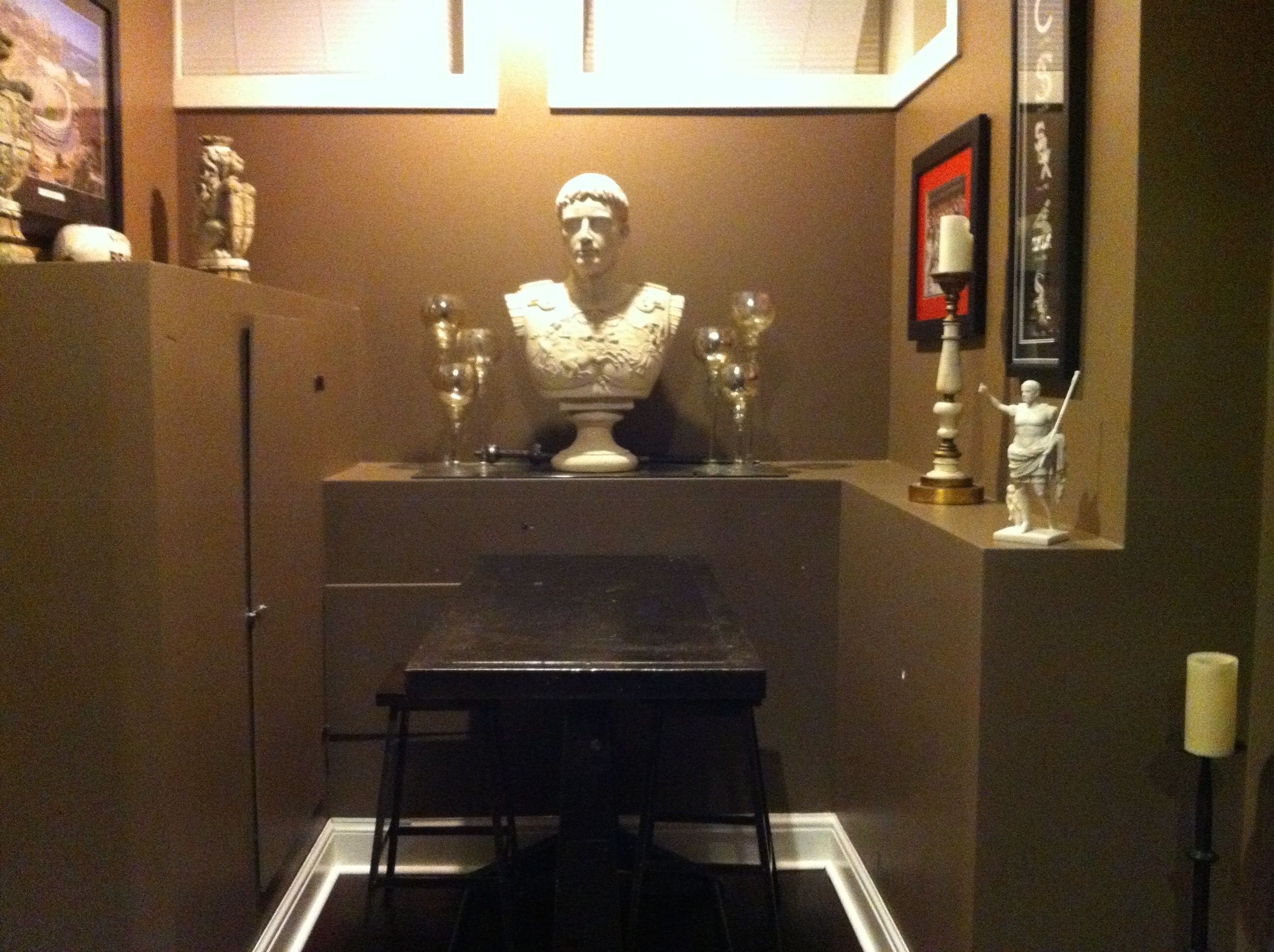 A small room with a table and chairs, a bust sculpture, and a few decorative items on the walls.