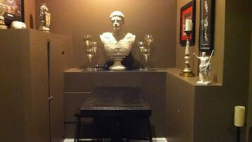 A small room with a table and chairs, a bust sculpture, and a few decorative items on the walls.