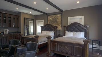A bedroom with two large beds, a sitting area with chairs, a wooden desk, and a large map on the wall.