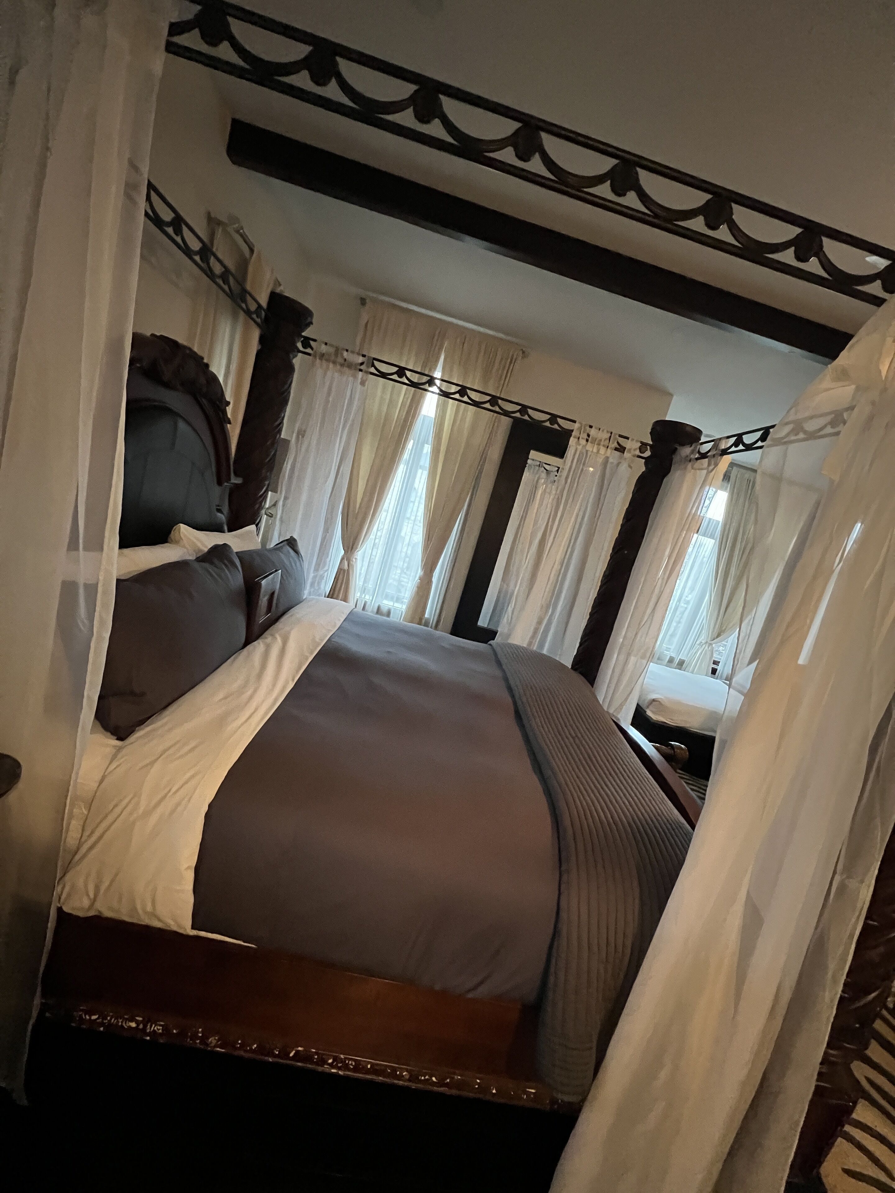Un lit à baldaquin, avec une tête de lit et une table de chevet.
