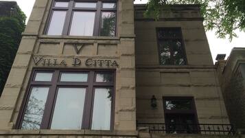 Villa D'Italia's facade with stonework, large windows, and a balcony.