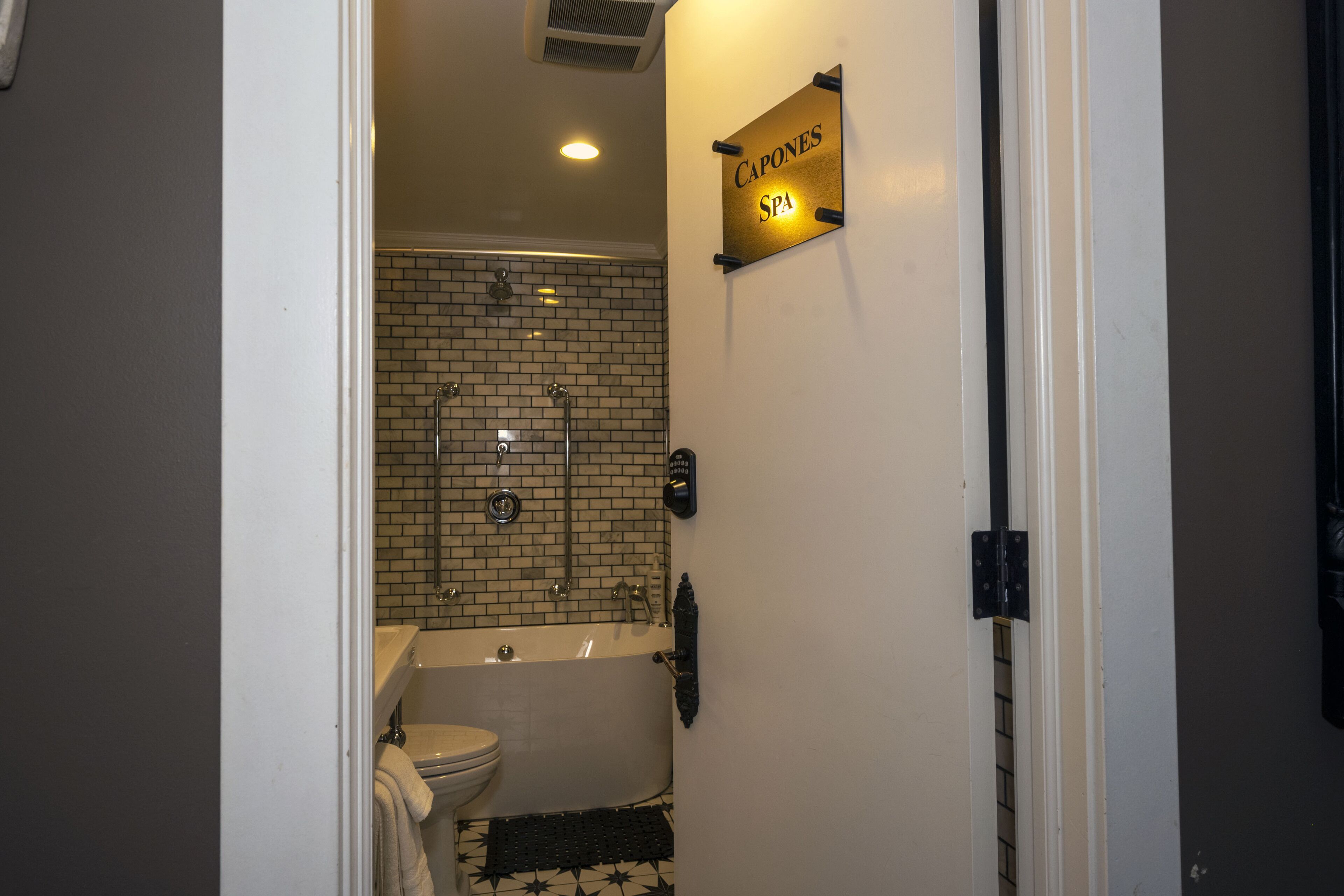 Kylpyhuoneessa on kylpyamme, wc ja suihku. Seinällä on kyltti, jossa lukee: ”Capones SPA”.