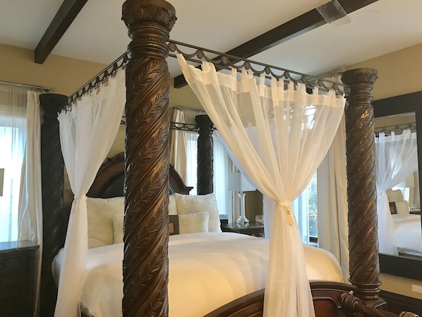 Un lit à baldaquin avec des draps blancs et un ciel de lit.