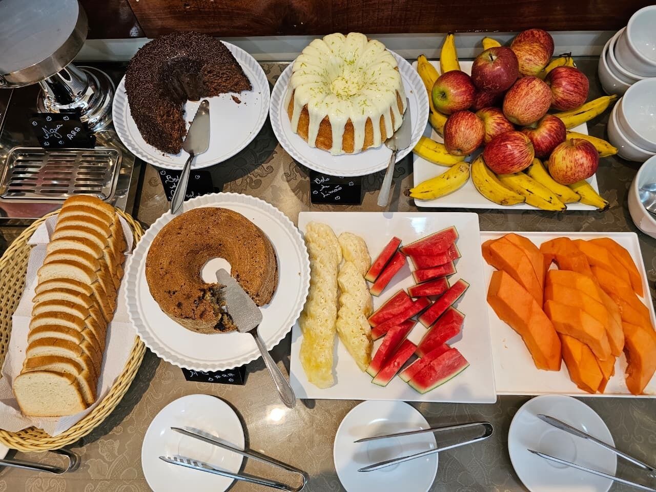 Un bufé con diferentes opciones de comida, como pasteles, frutas y verduras cortadas.