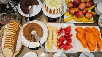 Un bufé con diferentes opciones de comida, como pasteles, frutas y verduras cortadas.