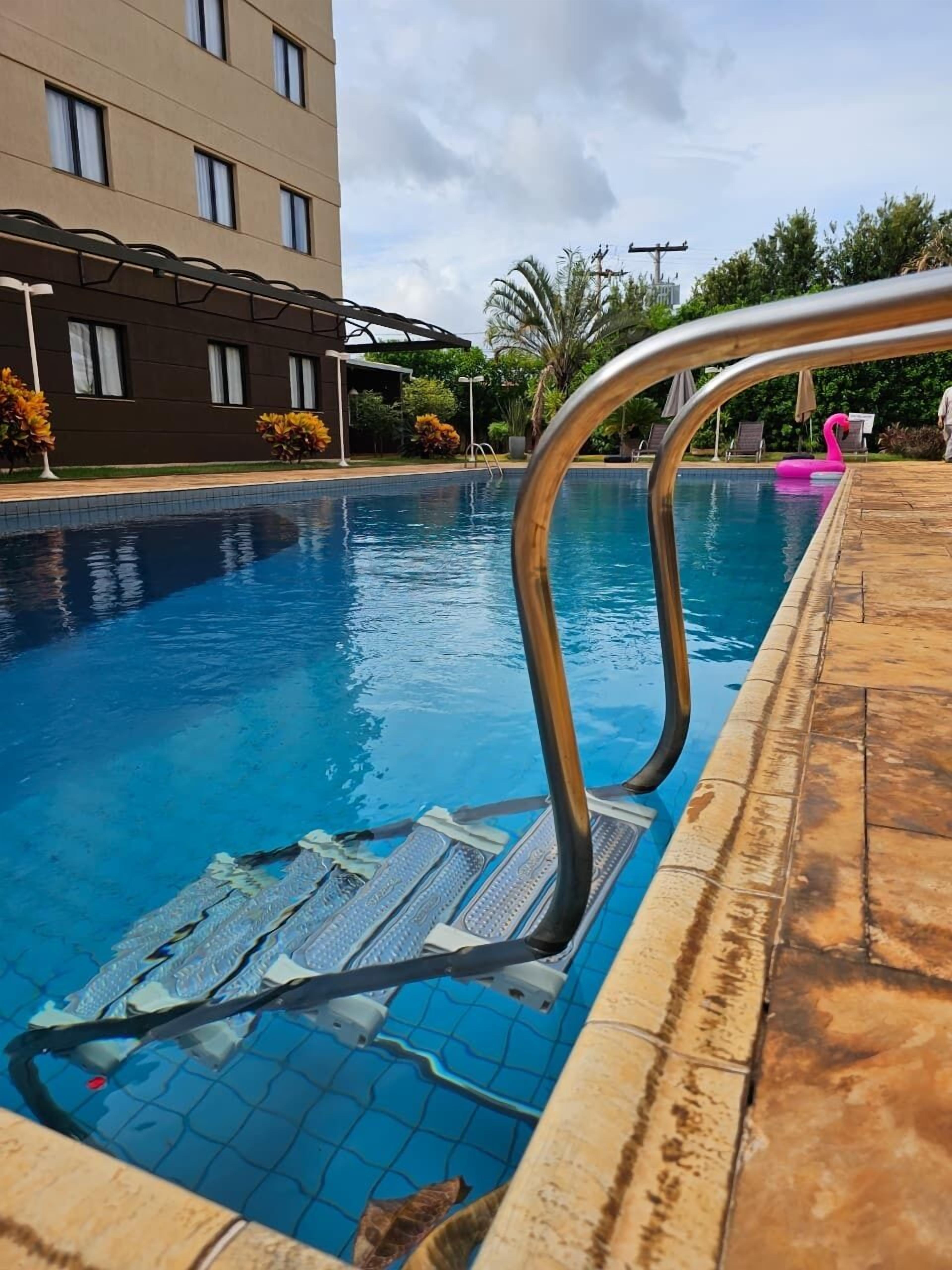 Una piscina al aire libre, sillones reclinables de piscina