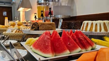 A buffet with various food items including watermelon, bread, and fruit.