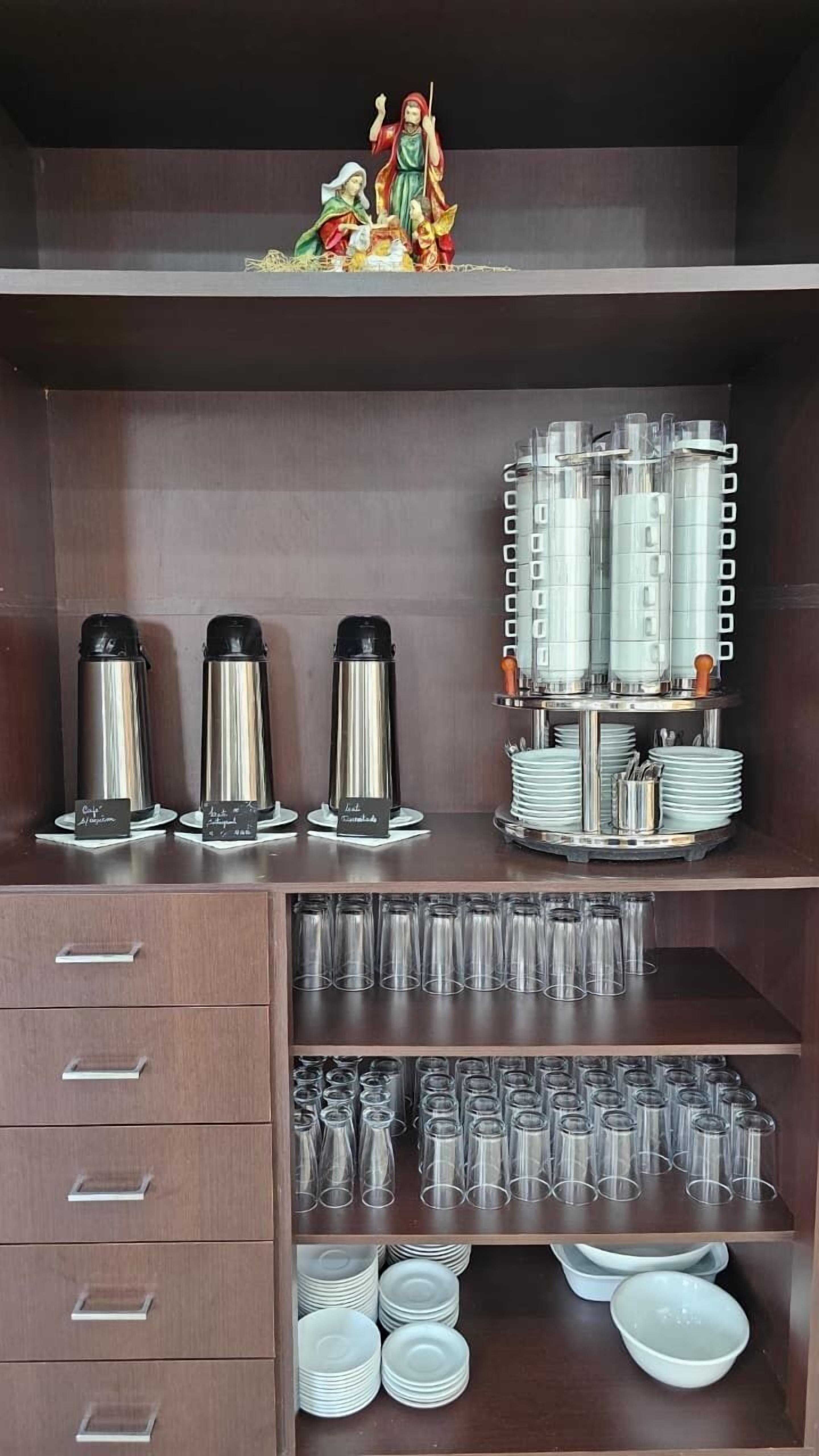 Une cuisine équipée d’appareils électroménagers en acier inoxydable, de verres et d’une statuette religieuse décorative.