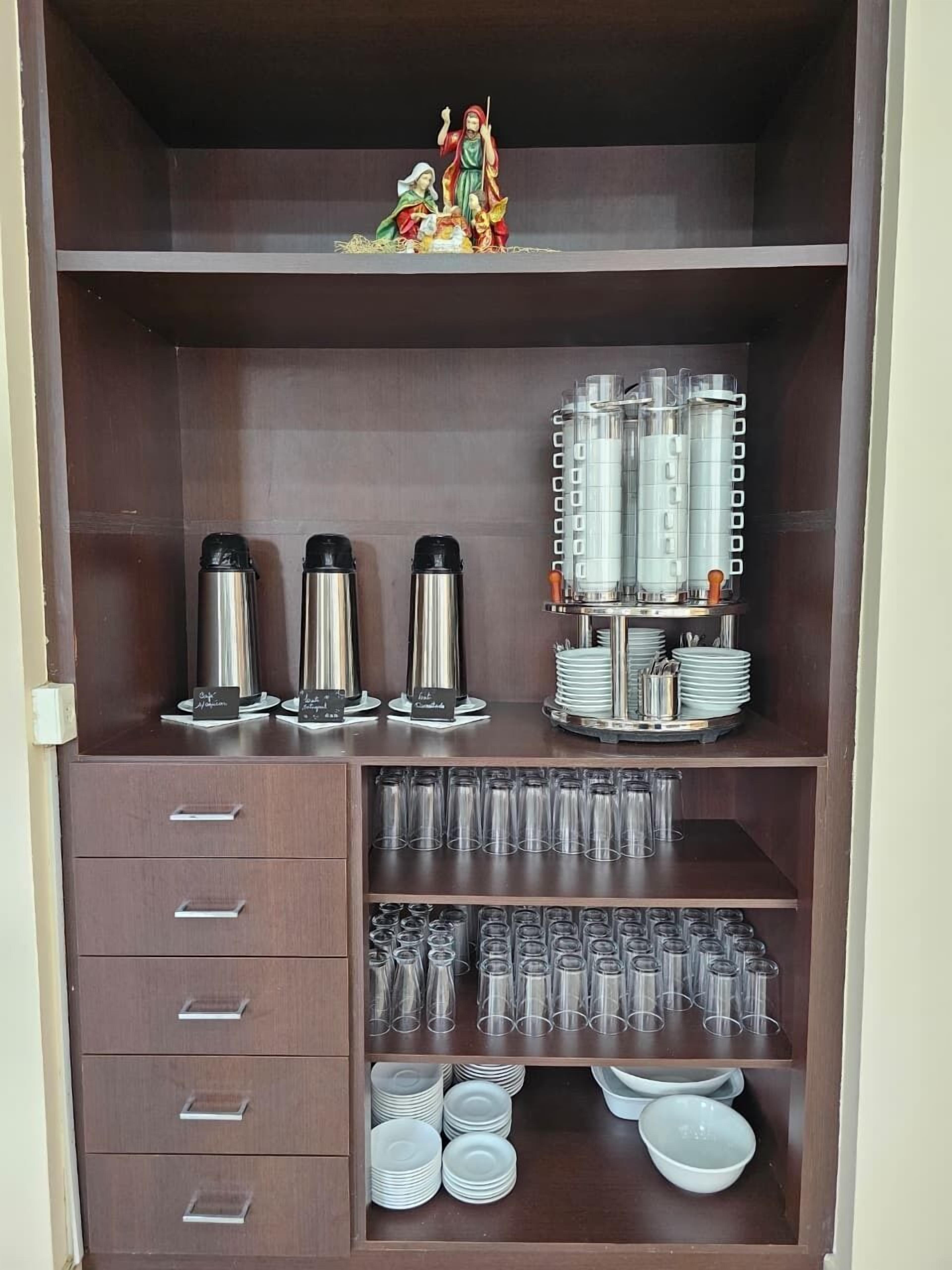 Una cocina con electrodomésticos de acero inoxidable, cristalería y una figura decorativa en la estantería.