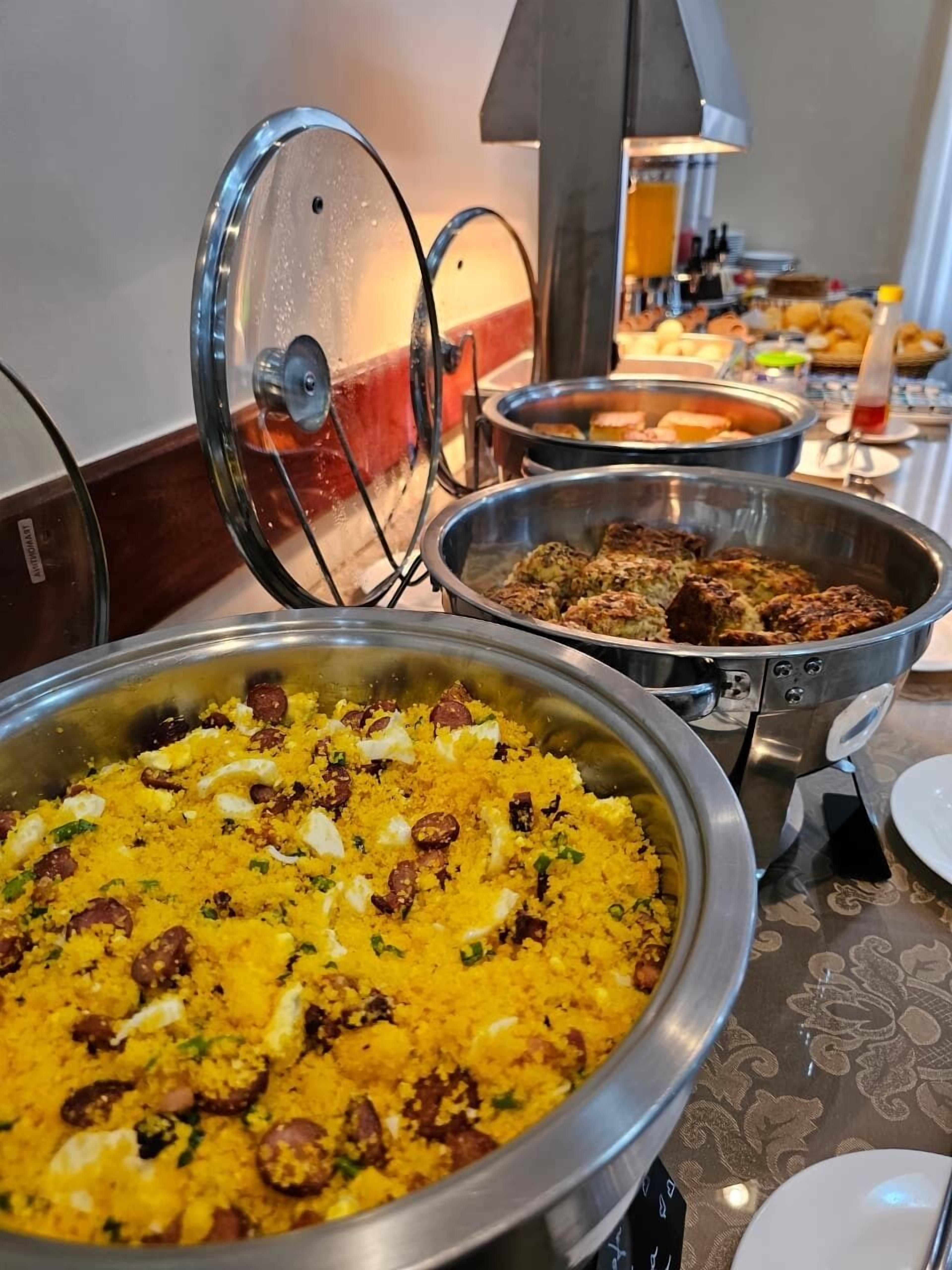 A buffet with various dishes, including a large bowl of yellow rice garnished with nuts and herbs.